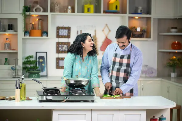 Güzel bayan kocası mutfakta yemek pişirirken gülümsüyor.