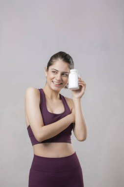 Akıllı bir kadın kafasını yana doğru eğiyor, elinde bir tablet şişeyle kameraya gösteriyor.