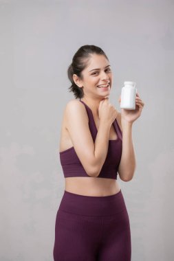 Sağlıklı vücutlu bir kadın bir fincan kahve tutuyor ve kameraya gülümsüyor.