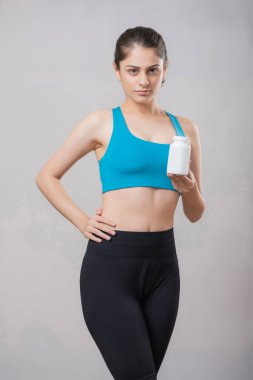 Elinde takviye şişesi tutarken yüzünde ciddi bir ifade olan oldukça olgun bir kadın.