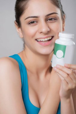 Vitamin şişesi tutarken güzel bir yüz resmi.
