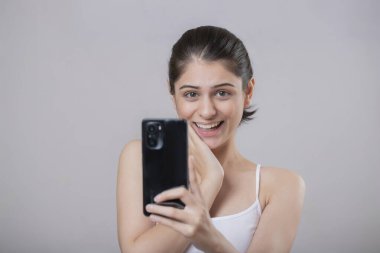 Moda kadını. Bir eli çenesinin altında ve akıllı telefon ekranına bakıyor.