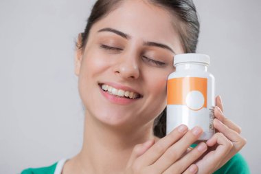 Kameranın önünde elinde kapsül şişesiyle poz veren güzel Hint mankeni.