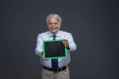 Yaşlı bir adam gülüyor ve tahtasını gösteriyor.
