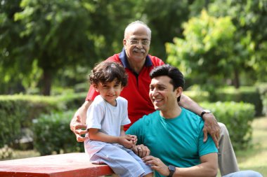 Parkta bankta oturan mutlu üç nesil. 