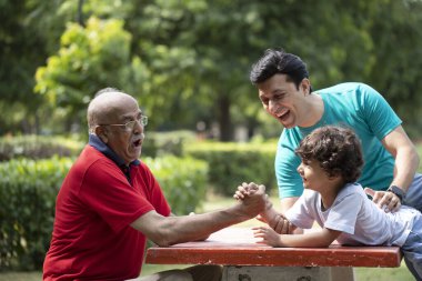Üç nesildir erkekler bahçede bilek güreşi yaparken eğleniyorlar.