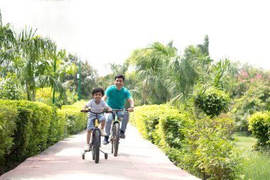 Oğul ve baba dışarıda bisiklet sürerken birlikte vakit geçiriyorlar