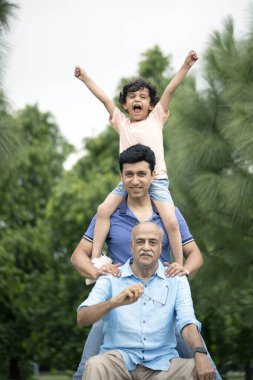 Mutlu adam kameranın önünde oğlu ve torunuyla poz veriyor.