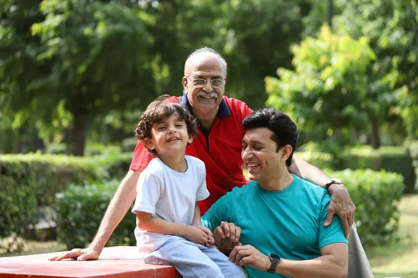 Ailedeki mutlu adamlar kameranın önünde poz verirken parkta oturuyorlar.