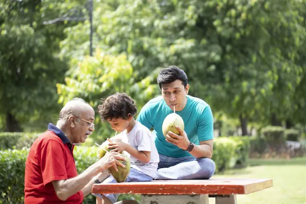 Baba oğluyla ve torunuyla yaz hindistan cevizi suyu içiyor.