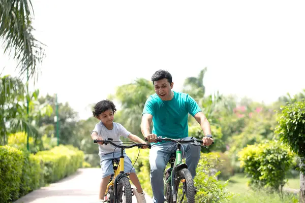 Baba ve oğul bahçede bisiklet sürerken eğleniyorlar 