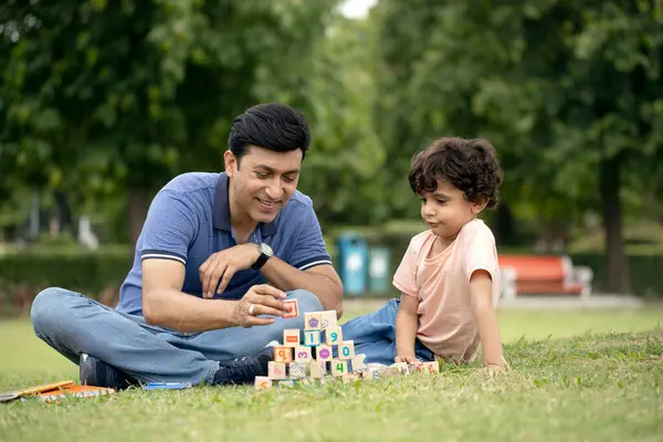 Baba ve oğlunun parkta bloklarla oynarken çekilmiş bir fotoğrafı.