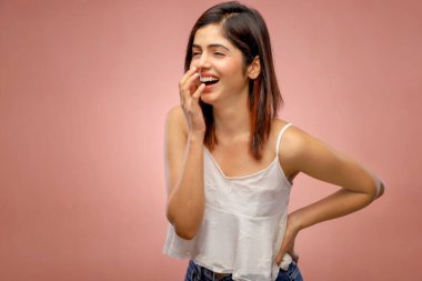 Gülen Hintli manken bir elini belinde, diğerini ağzında tutuyor.