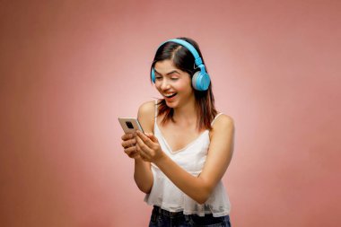 Gülümseyen, beyaz etekli güzel bayan elinde cep telefonu tutuyor.