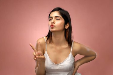 Çekici bir kadın dikilip kameraya doğru poz veriyor.