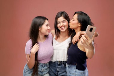 Elleri omuzlarında üç bayan arkadaş selfie çekiyorlar.