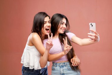 Two besties are smiling while clicking a photo and making a victory hand sign clipart