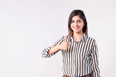 Resmi giyinmiş bir kadın beyaz arka planda dururken işaret veriyor.