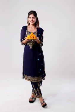 Mavi Hintli etnik elbiseli hoş bir bayan laddoo tabağını elinde tutuyor.