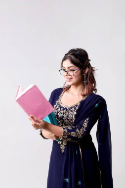 Gözlüklü, kitap okuyan ve elinde gri arka planda kitap tutan bir kadının yan pozu