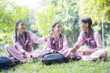 Okul bittikten sonra genç bir kız ve arkadaşları okul parkında dinlenirken gülüyorlar.