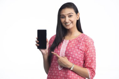 Güzel, gülümseyen bir kadın akıllı telefonu elinde tutarken