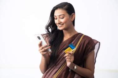 Saree 'deki mutlu eş kredi kartı tutuyor ve online alışveriş için akıllı telefon kullanıyor. Çevrimiçi alışveriş kavramı