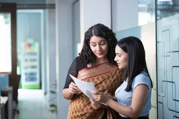 İki iş kadını planlama veya finansman için ofiste belgeleri tartışıyor