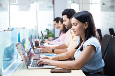 Yönetmen hanım, ekibiyle birlikte dizüstü bilgisayarda çalışıyor.