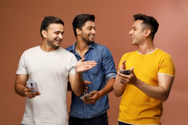 Üç havalı arkadaş kameranın önünde dikilirken cep telefonlarında video izlemekten zevk alıyor.