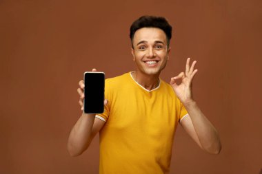 Çekici bir adam Mobil ekranı gösterirken iyi bir el hareketi yapıyor.