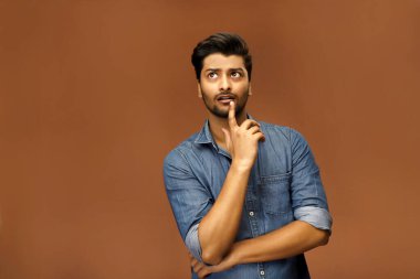 Çekici bir erkek model parmağını çenesinde tutarken bir şeyler düşünür.