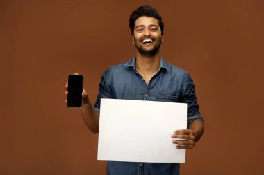 Pozitif bir adam bir elinde boş bir kağıt, diğer elinde cep telefonu tutuyor.