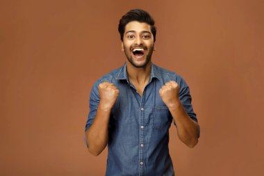 Heyecanlı bir erkek model, yumruklarını sıkarak başarısını kutluyor.