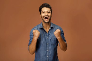 Mutlu bir erkek model, yumruklarını havaya kaldırarak başarıyı kutluyor.