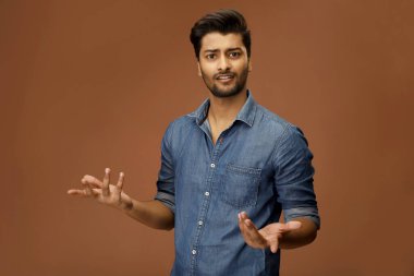 Kafası karışmış bir adam kameranın önünde ellerini kaldırıyor.