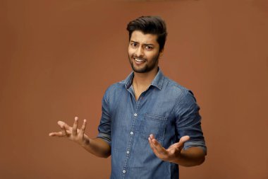 Kot gömlekli rahatsız bir adam omuz silkme hareketiyle poz verir.