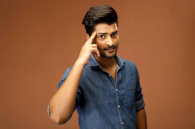 Ciddi bir adam parmağını başının üstünde tutuyor ve kameraya bakarken düşünüyor.