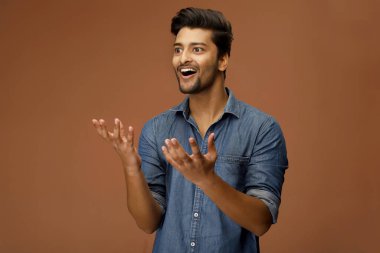 Hintli bir erkek model kameranın önünde poz verirken heyecanla ellerini açıyor.