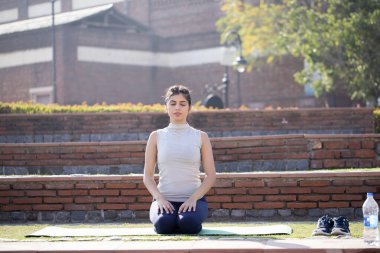 Genç çekici kadın Vajrasana 'da oturuyor, Thunderbolt veya Diamond poz veriyor.