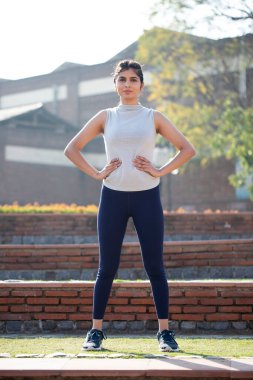 Fit Kadın Model Kameranın önünde duruyor Ellerini kalçasında tutuyor