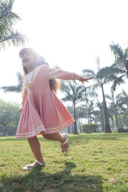 Güneşli bir günde parkta koşan bir kız