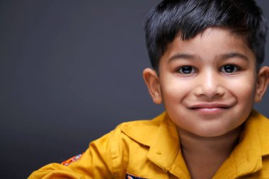 Yllow gömlek giymiş gülümseyen bir çocuk kameraya bakıyor ve poz veriyor.