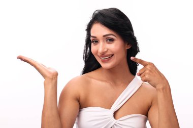 Çekici genç bir kadın sıcak bir şekilde gülümser, avucunu kaldırıp ona bakar, dikkat çeker..