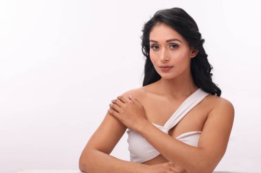 Güzel bir manken zarif bir şekilde poz verir zarif saçlarını göstererek minimalist bir ortamda.