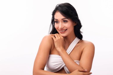 Çekici genç bir kadın beyaz bir stüdyo geçmişine karşı özgüvenle poz veriyor. Zarafet ve cazibe yayıyor..