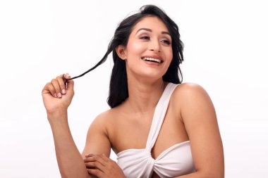 Gülümseyen bir kız, uzun, güzel saçlarına dokunurken neşeli bir şekilde flört eder..