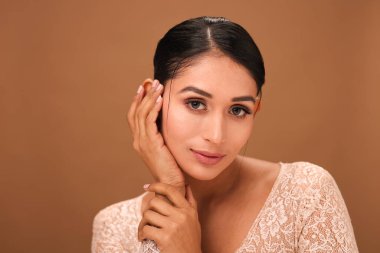 Asyalı bir kadının rahat ve içerik ifadesiyle doğrudan kameraya baktığı yakın çekim görüntüsü.