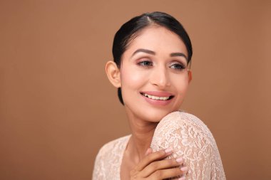 Çekici, çekici bir kadın. Parlak bir gülüşü var. Tarafsız, kahverengi bir arka plana karşı kendine güveni var..