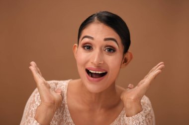 Şaşırmış bir kız ağzı açık ve eli nazikçe yanağına yerleştirilmiş bir şekilde şaşkınlığını ifade eder. Şaşkın bakışları heyecan ve merak dolu bir anı yakalıyor..